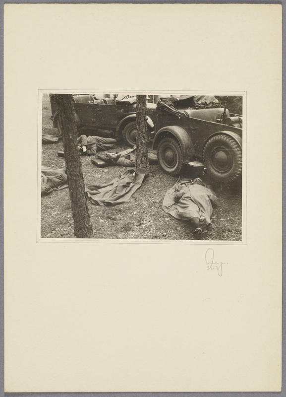 Soldaten schlafen auf dem Boden vor zwei Militärfahrzeugen, recto