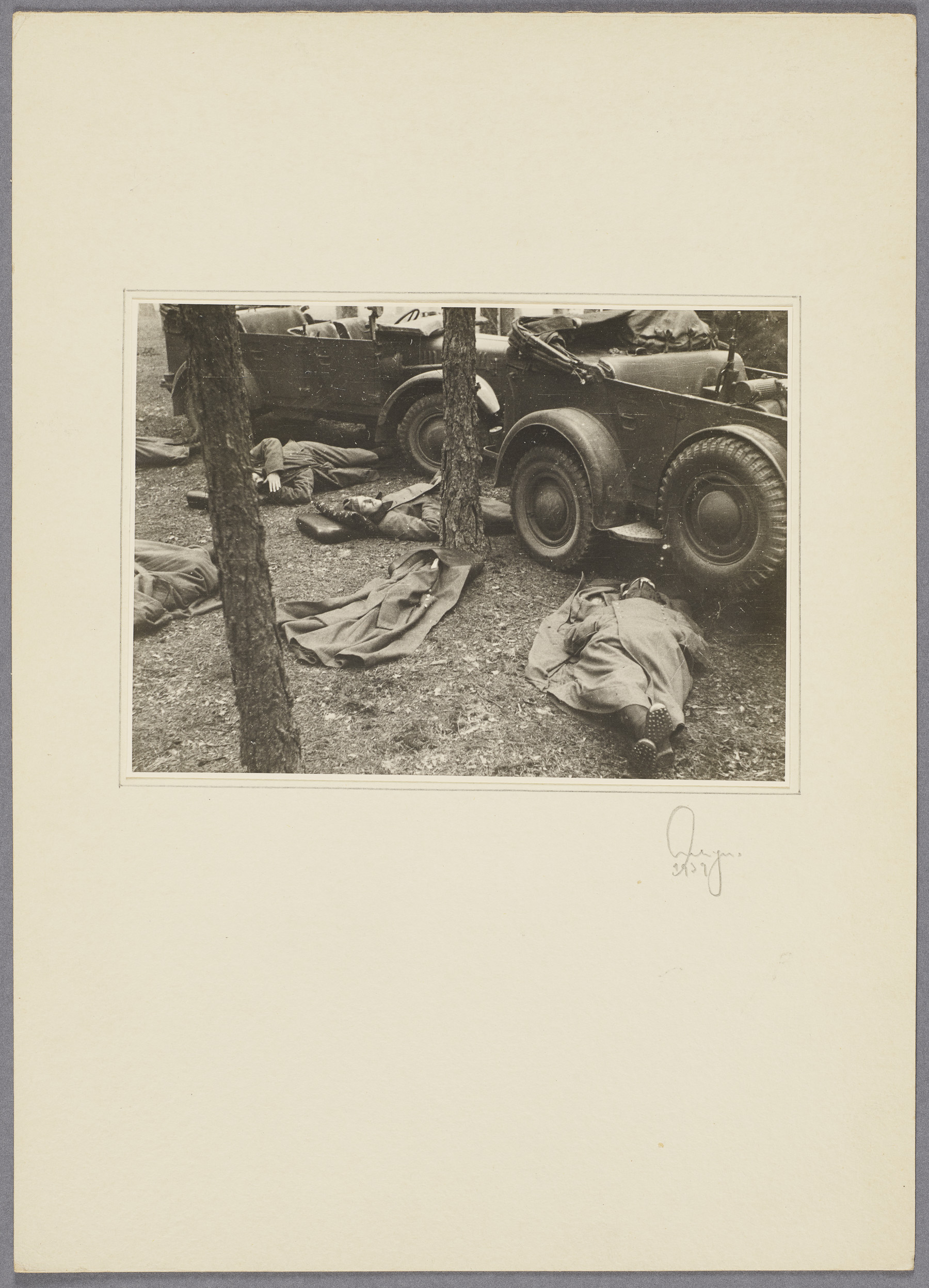 Soldiers sleeping in front of military vehicles